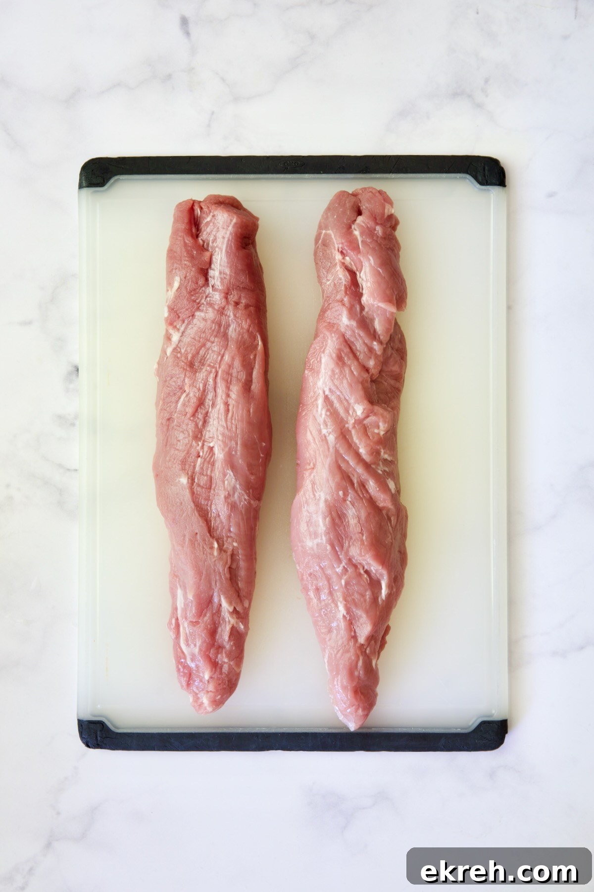 Grilled Citrus Mojo Pork Tenderloin Skewers 6 Two trimmed pork tenderloins on white plastic cutting board.