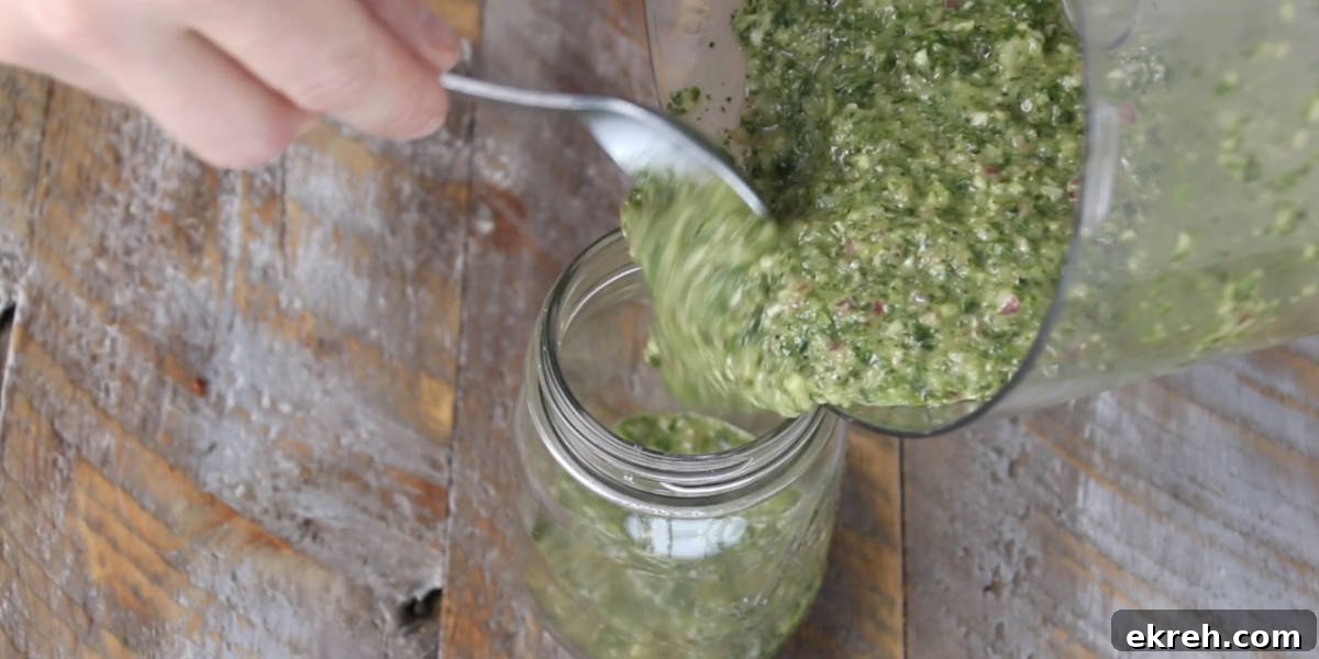 dumping chimichurri into mason jar from food processor