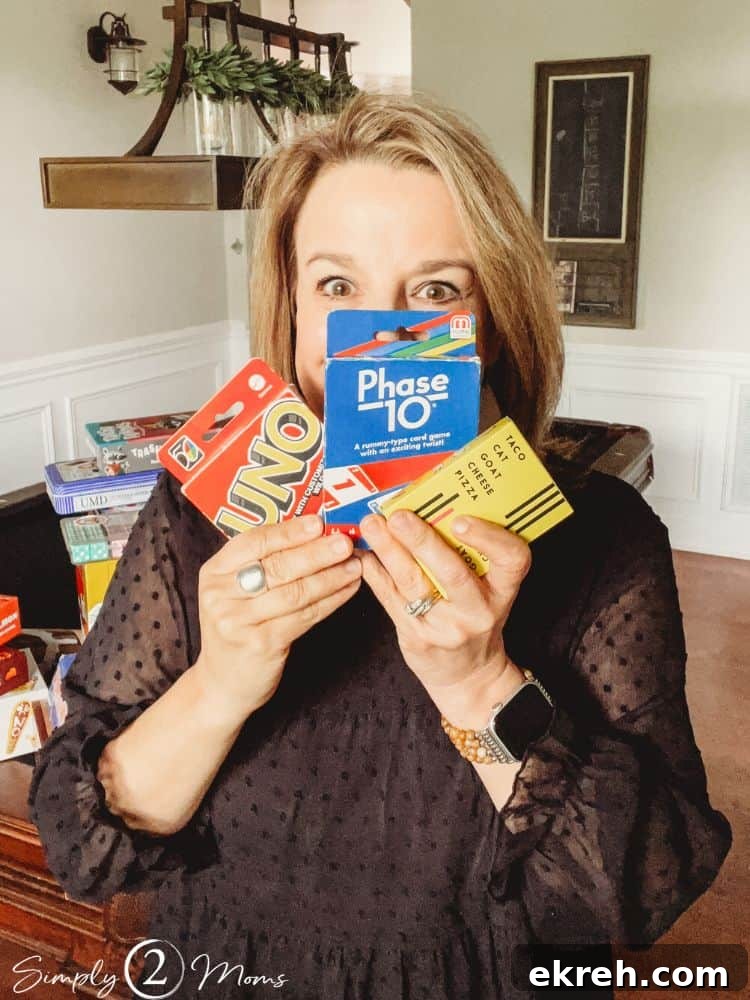 Simply Stated Episode 49: Actionable Insights 9 Anne from Simply2Moms holding decks of cards to play Uno, Phase10, and Taco Cat Goat Cheese Pizza.