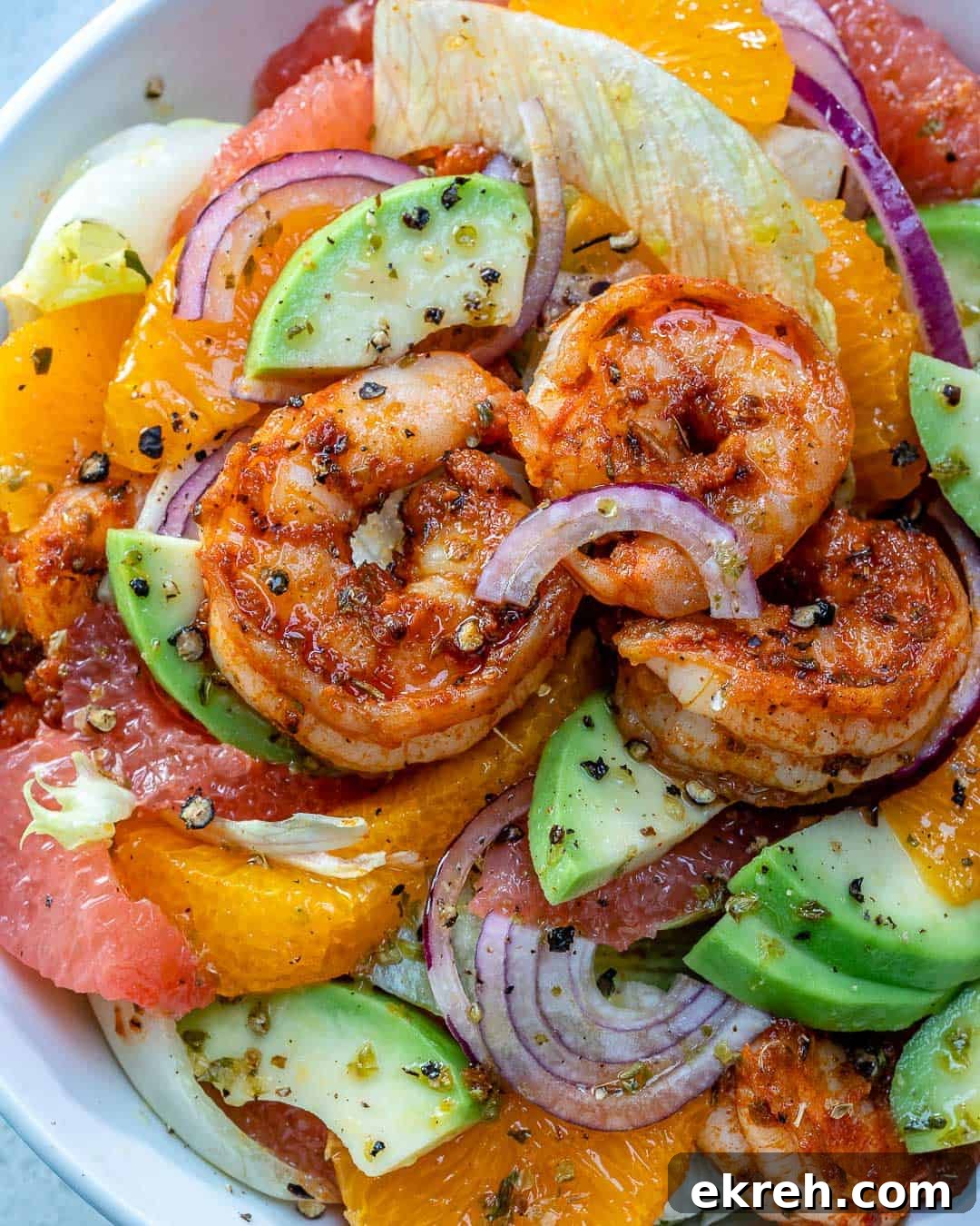 shrimp salad in a white dish with slices of avocados.