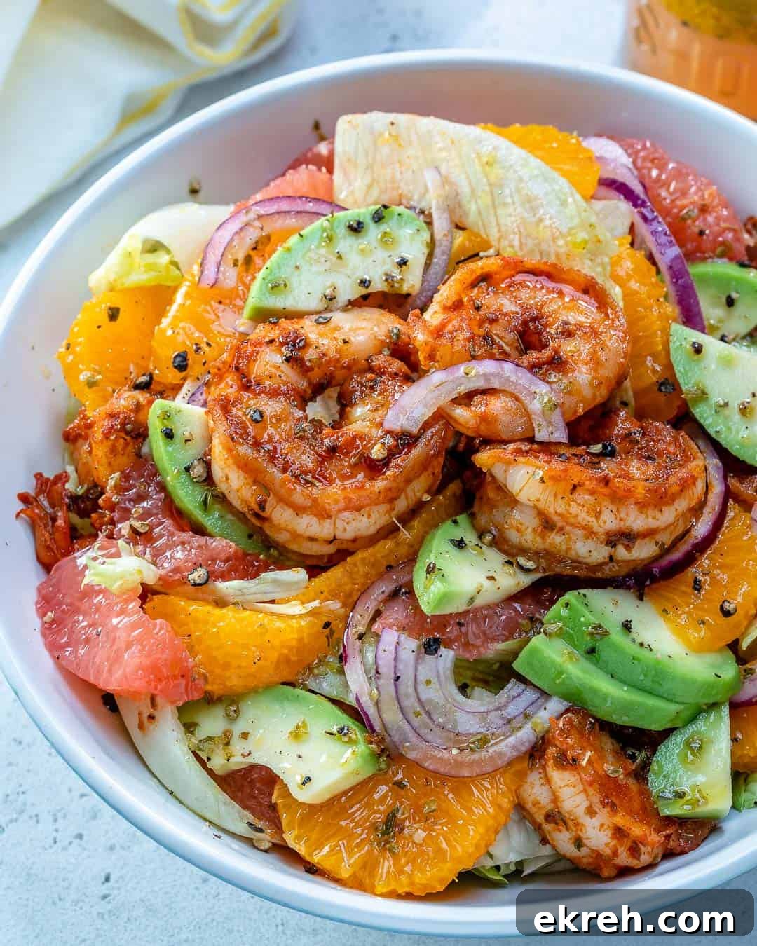 a round white bowl with shrimp, avocados, and sliced oranges and grapefruit.