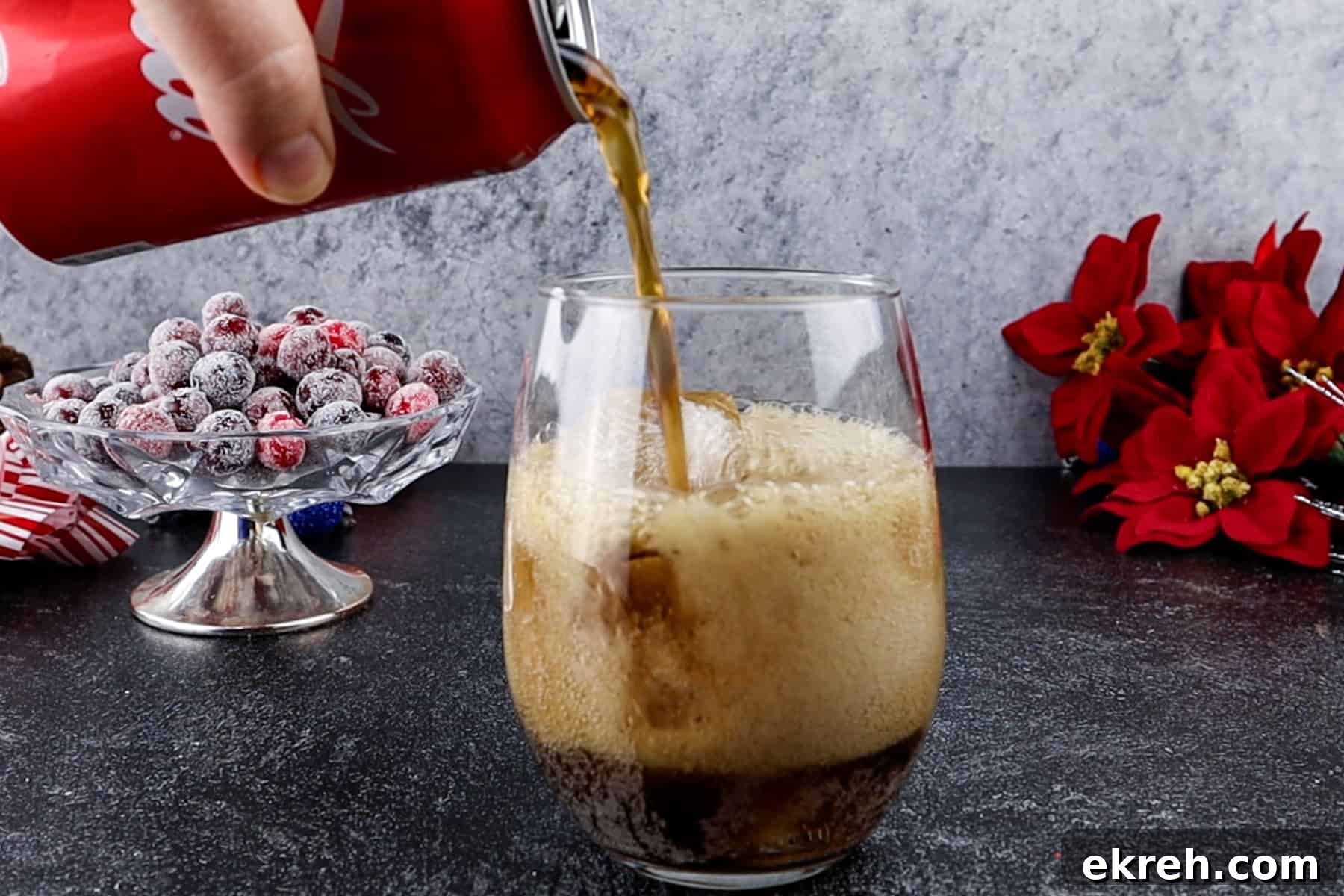 Quick Christmas Cocktail Recipe 5 Adding soda to a glass with ice in it.