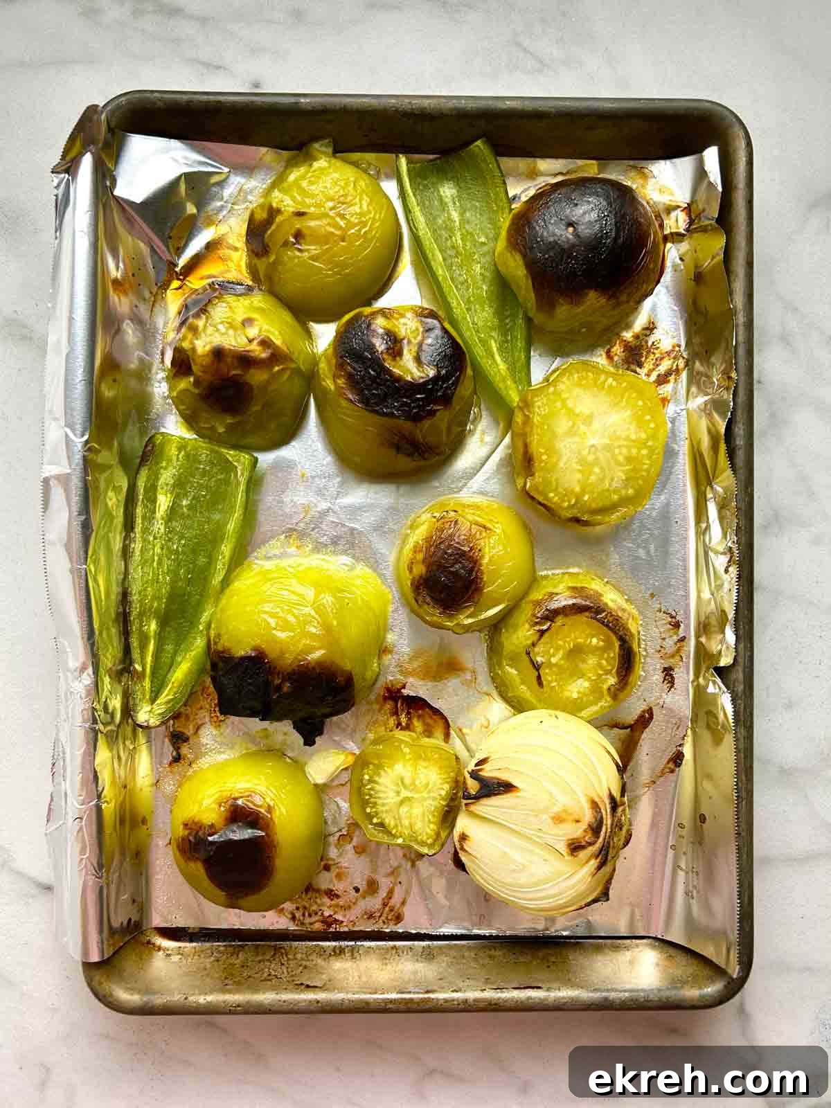 tomatillos, jalapeños, and half an onion after roasting; visibly charred.