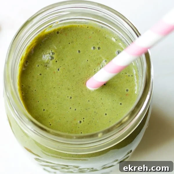 Overhead view of strawberry kale smoothie in mason jar with pink and white striped straw