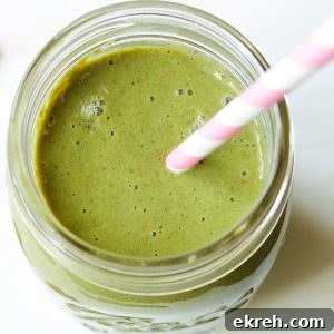 Overhead view of strawberry kale smoothie in mason jar with pink and white striped straw