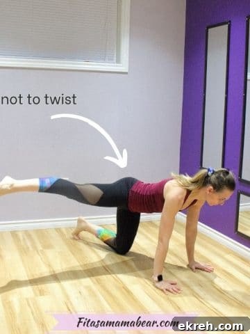 Woman in maroon shirt and black pants on her hands and knees performing a glute exercise.