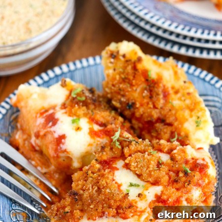 Olive garden style stuffed shells served on blue plates, and a fork on the side.