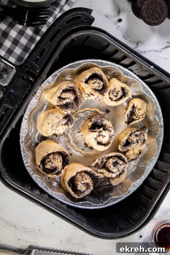 Air Fryer Oreo Cinnamon Rolls with Crunchy Oreo Swirl 4 Overhead view of a pan of uncooked oreo cinnamon rolls in an air fryer basket.