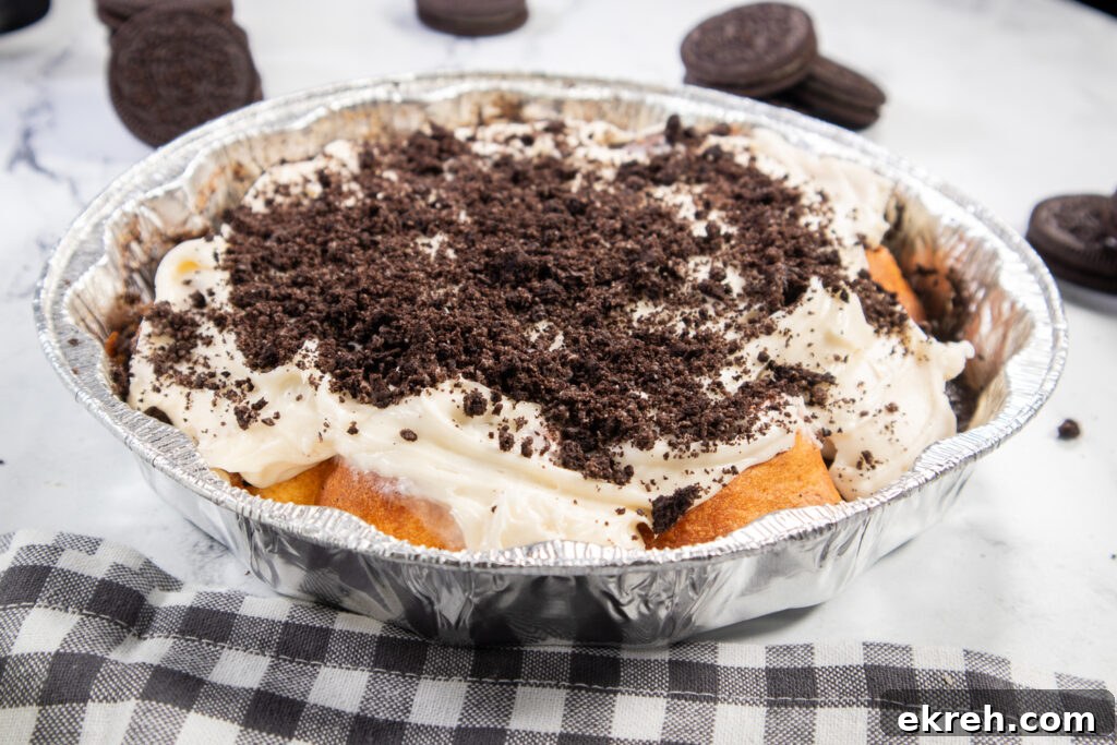 Air Fryer Oreo Cinnamon Rolls with Crunchy Oreo Swirl 5 Air Fryer Oreo Cinnamon rolls topped with cream cheese frosting and crushed Oreo pieces next to a linen napkin.