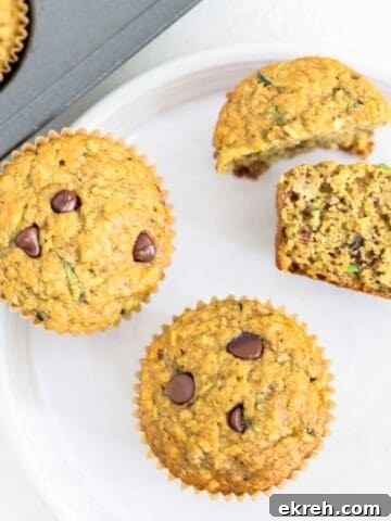 Two whole and two half banana zucchini chocolate chip muffins on a white plate.