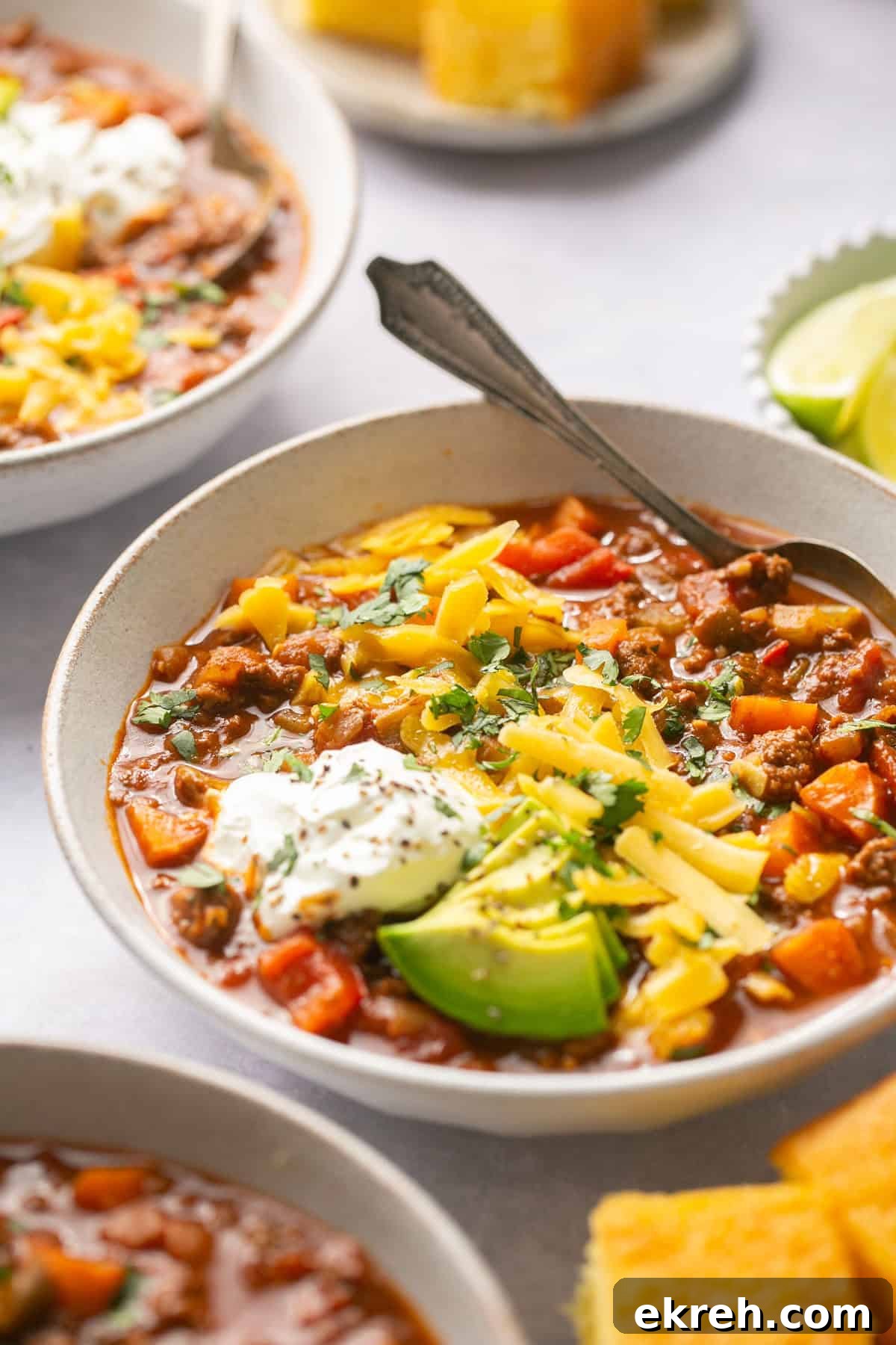 a side view of beanless chili in a bowl with toppings