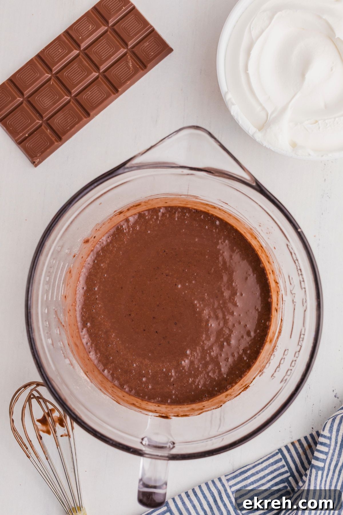 Chocolate cake mix batter mixed in a clear glass bowl on a white marble table. 