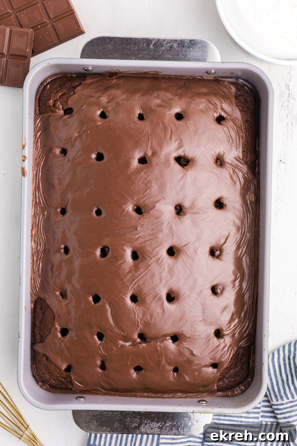 Melted chocolate and sweetened condensed milk poured into holes in a chocolate cake. 