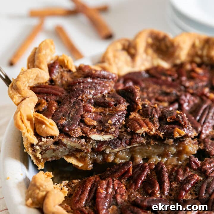 How to Make Apple Pie Filling from Scratch 12 A slice of pecan pie being pulled from the pie with plates and cinnamon sticks in the background.