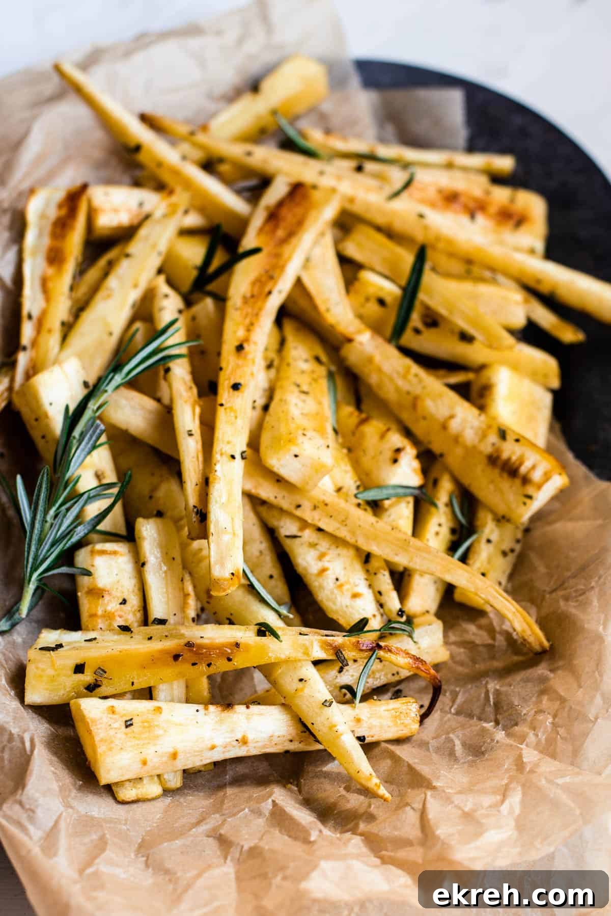 Crispy Oven-Roasted Parsnips with Garlic and Herbs 6 a pile of roasted parsnips on a black plate
