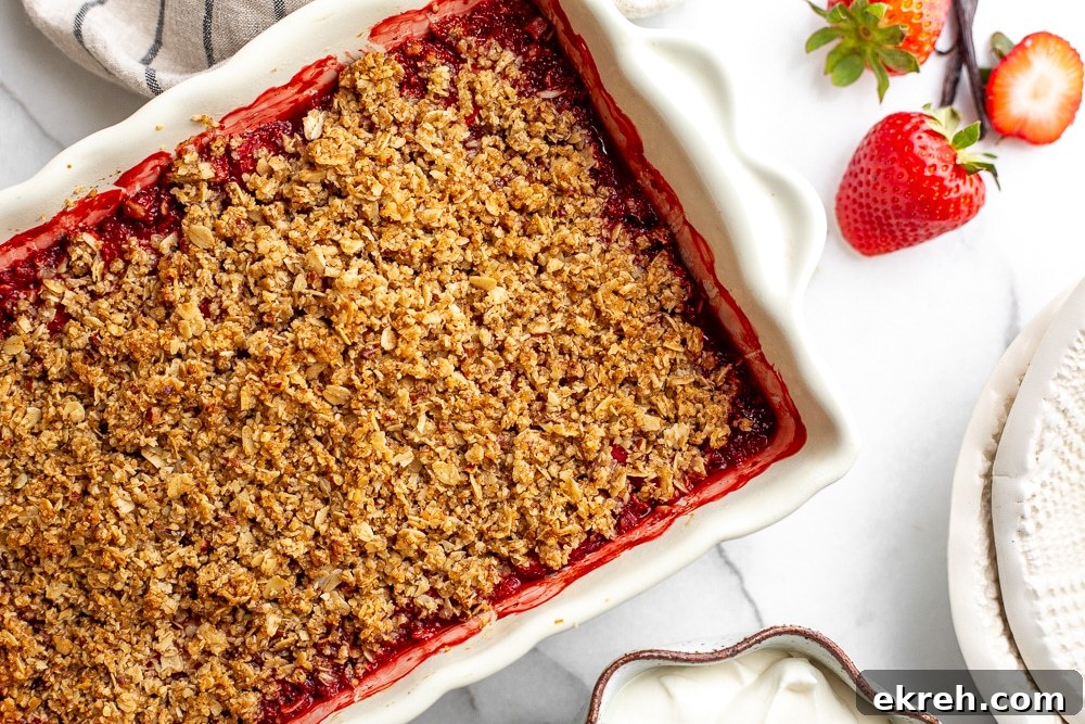 Gluten free strawberry crisp in baking dish with serving bowls alongside