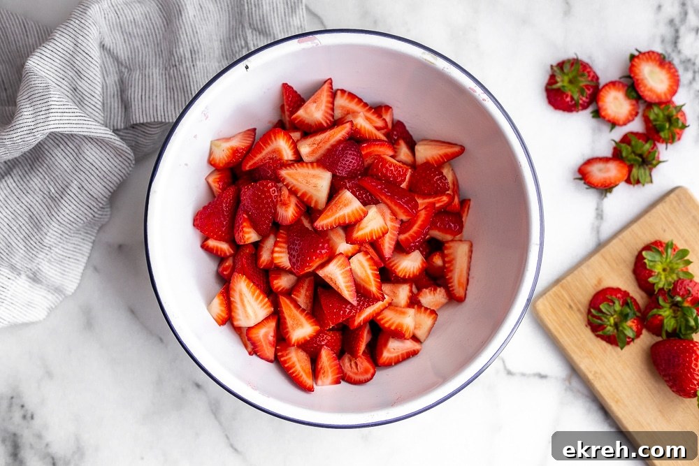 Chopped strawberries in bowl with cutting board on the side