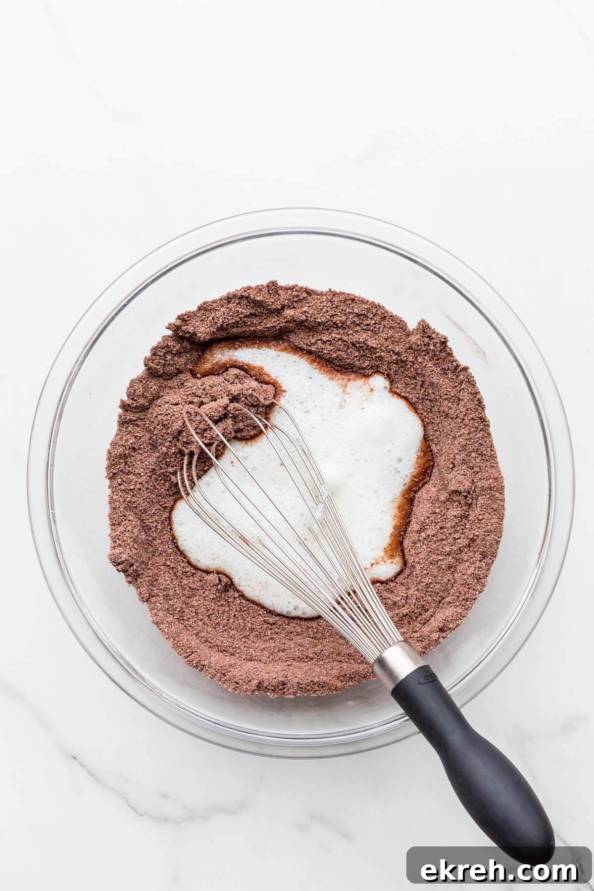Incorporating whipped egg whites with dry ingredients with a whisk to make financiers.