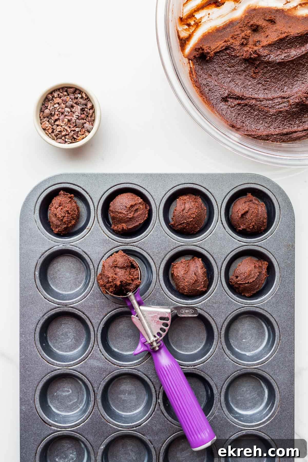Portioning chocolate batter into buttered muffin pan with a cookie scoop (disher) to make financier cakes.