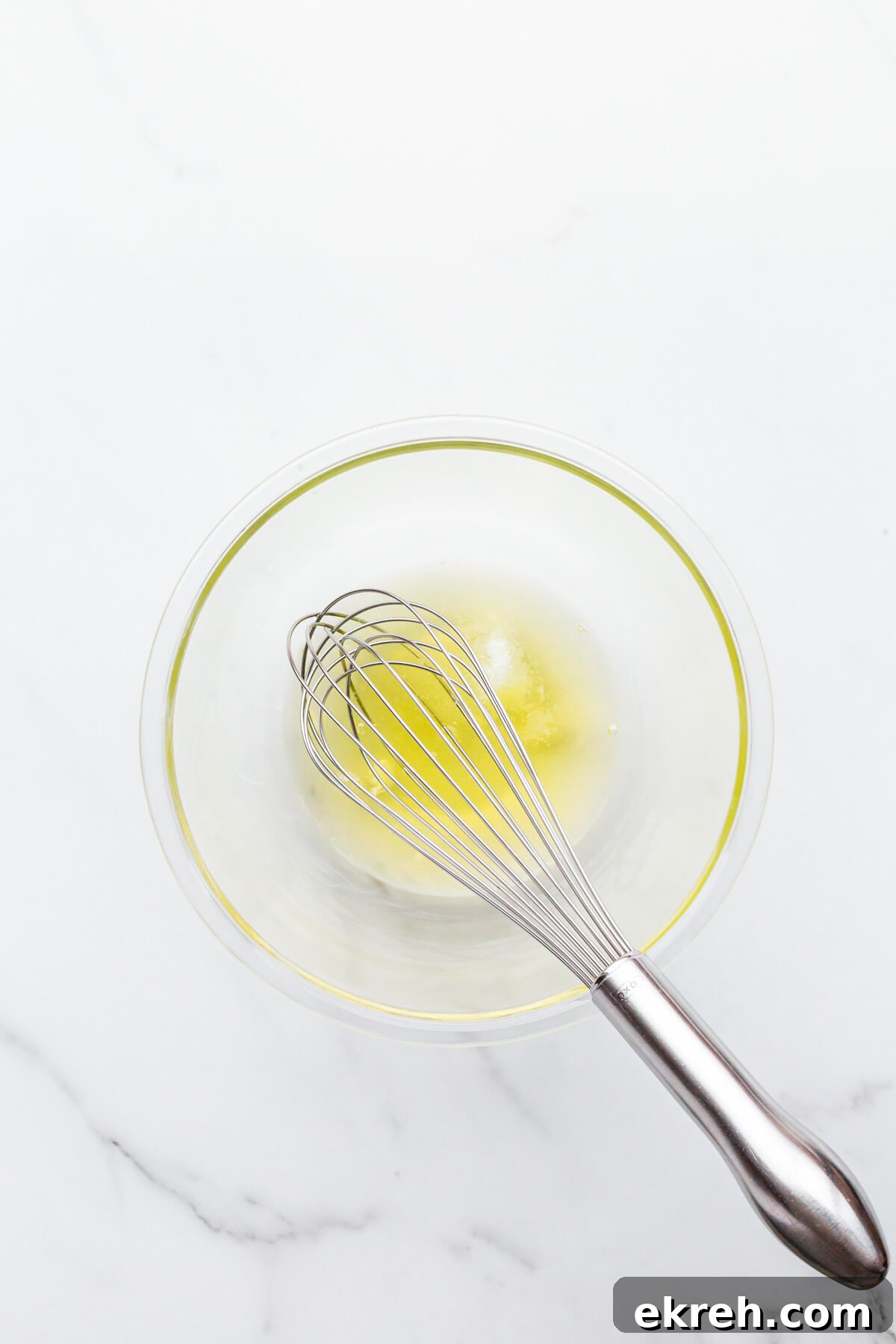 Egg whites in a glass bowl with a whisk that are ready to be whipped to make financiers.