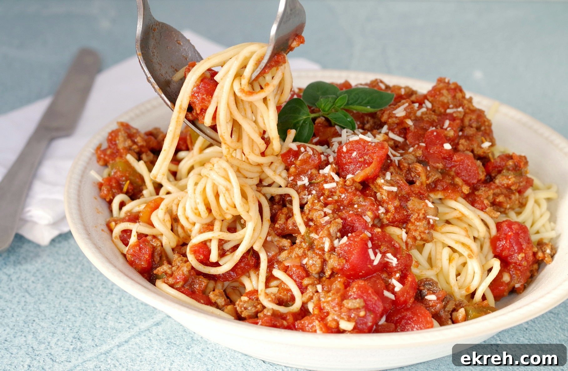 Spaghetti and meat sauce with spaghetti being twirled on fork with spoon