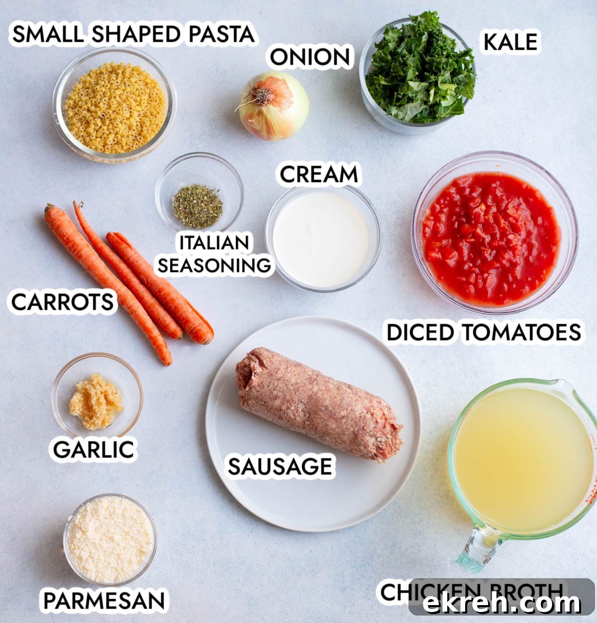 Ingredients in Creamy Italian Sausage Pasta soup on a gray background, labeled with black text. 