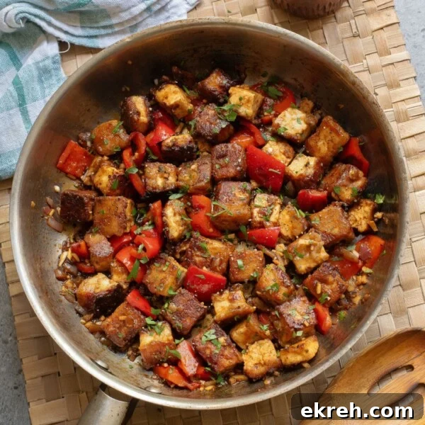 An overhead image of Indian chilli paneer in a stainless steel skillet.