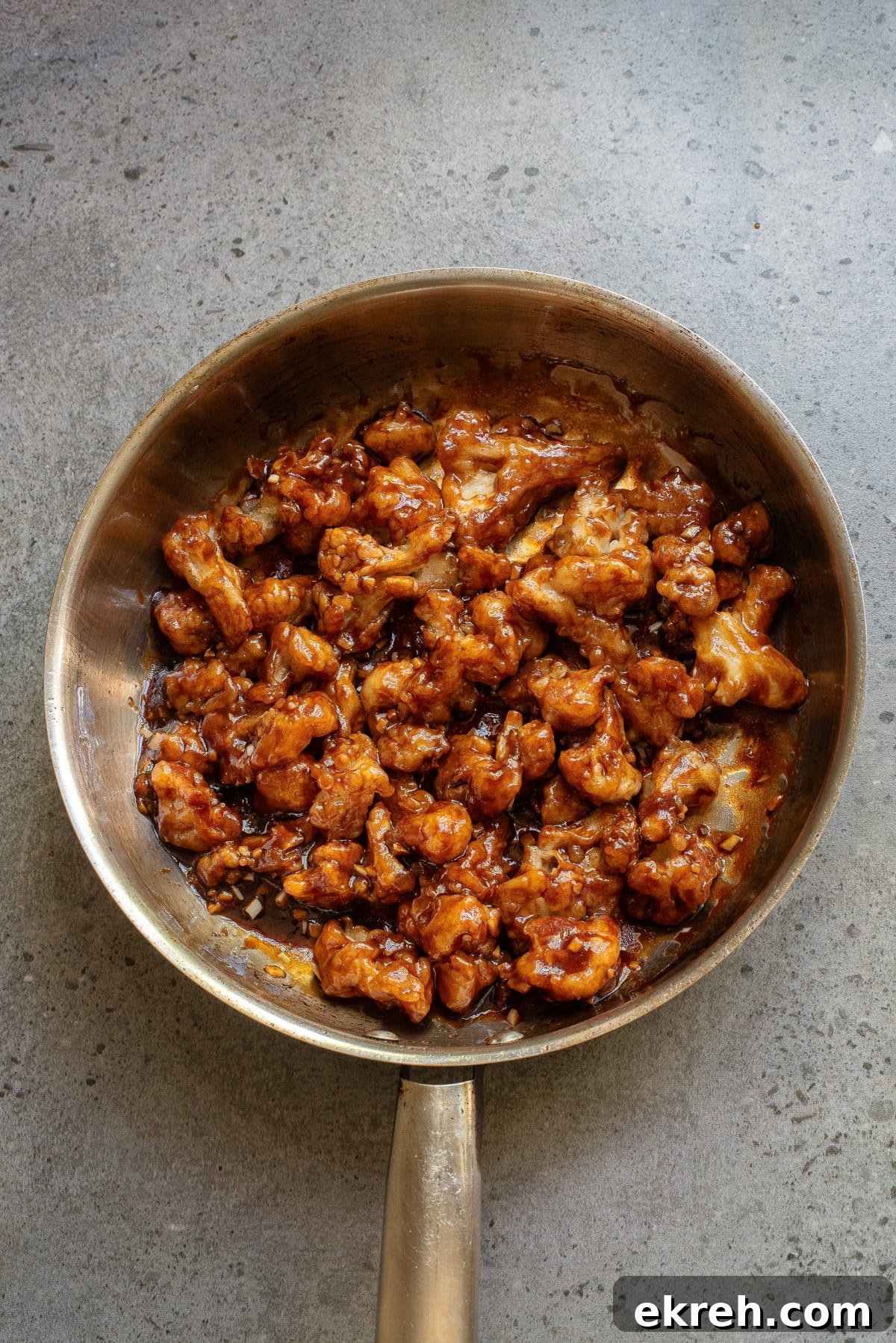 An overhead image of mixing the fried cauliflower with the sauce.