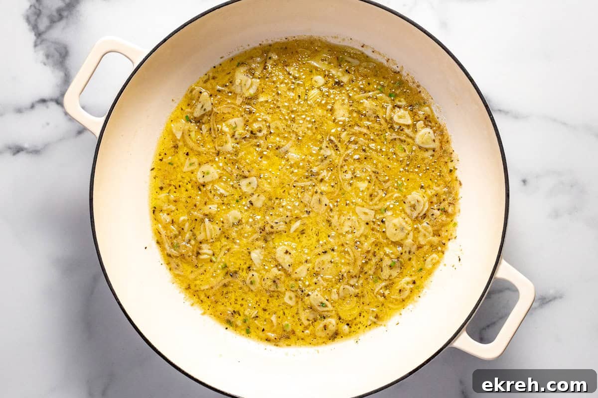 White skillet with olive oil butter garlic and herbs