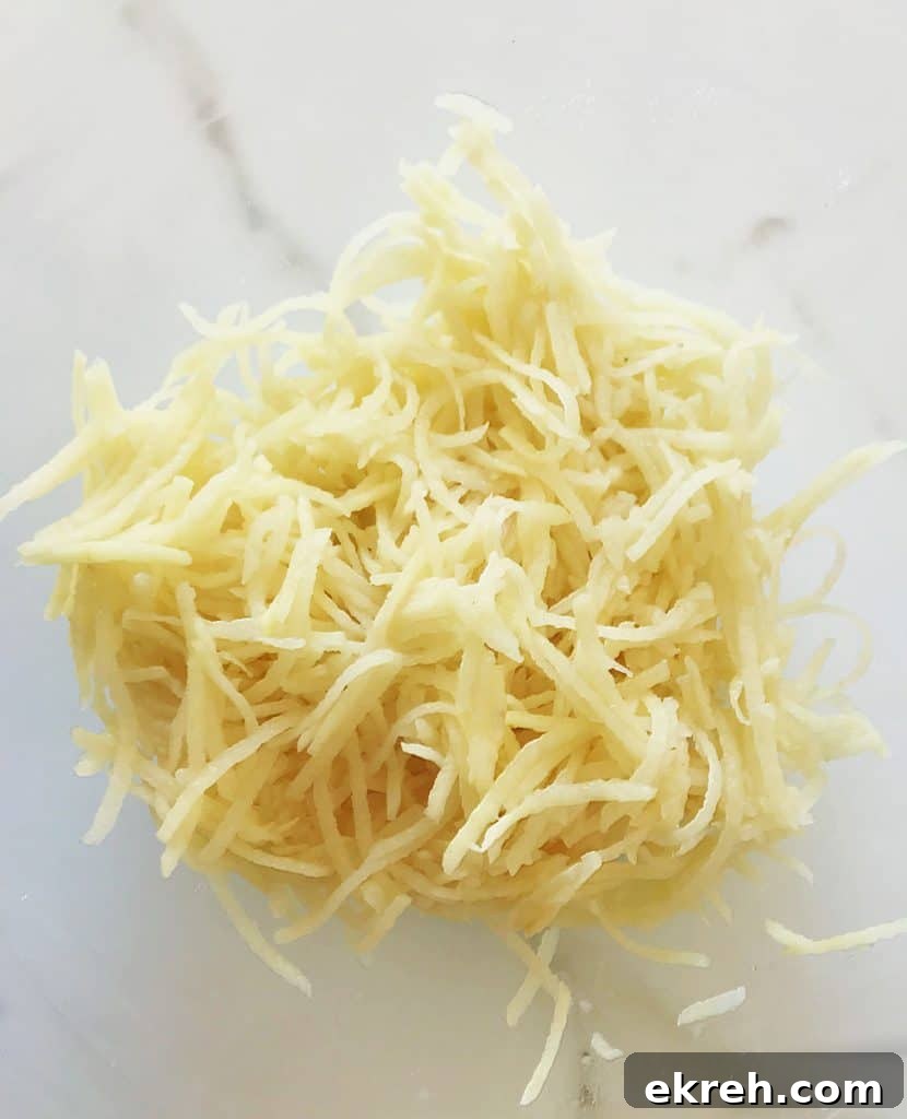 Shredded raw potato on white marble surface