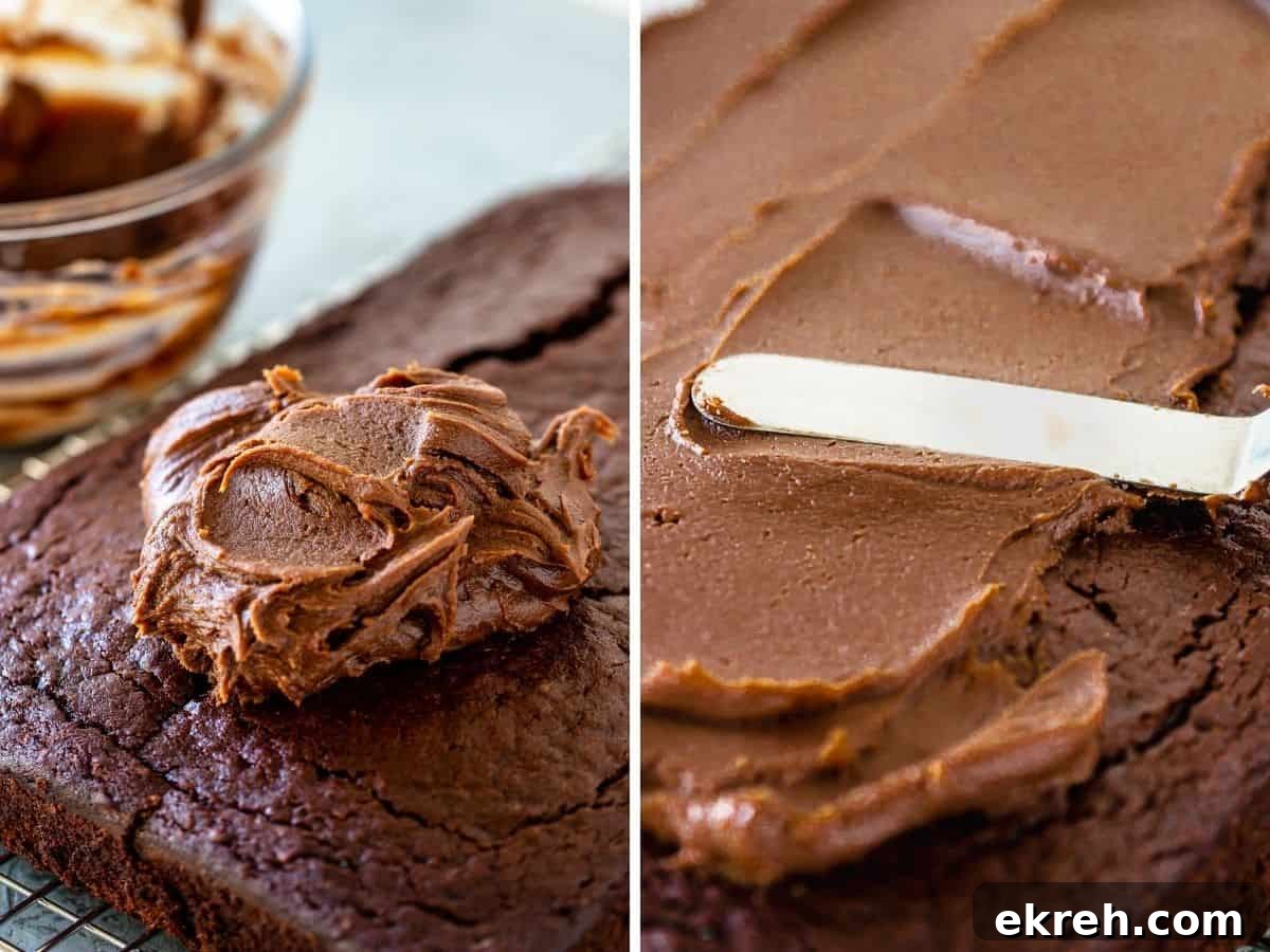 Chocolate frosting in a mound and being spread with spatula on rectangular chocolate cake