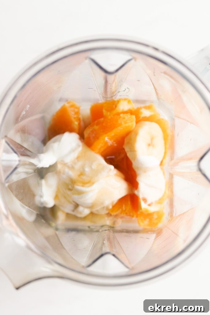 orange, banana, yogurt, honey, almond milk, vanilla, and ice in a blender