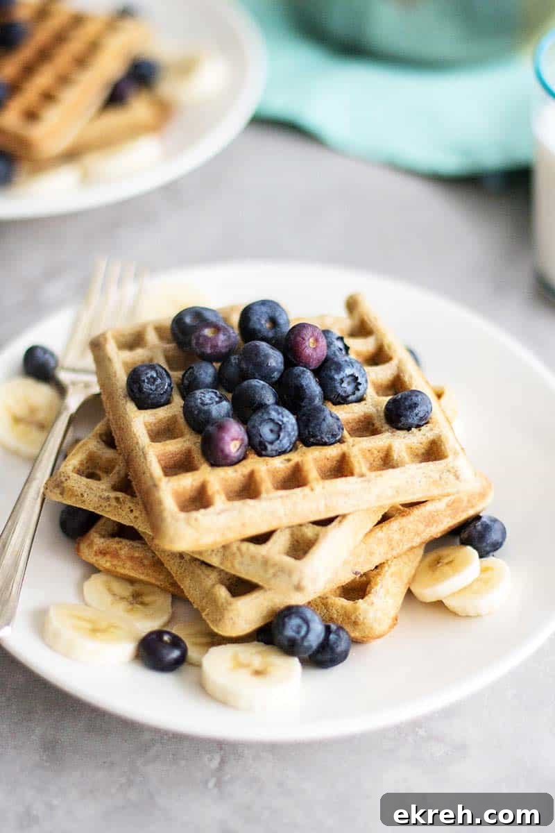 A stack of waffles with bananas and blueberries.