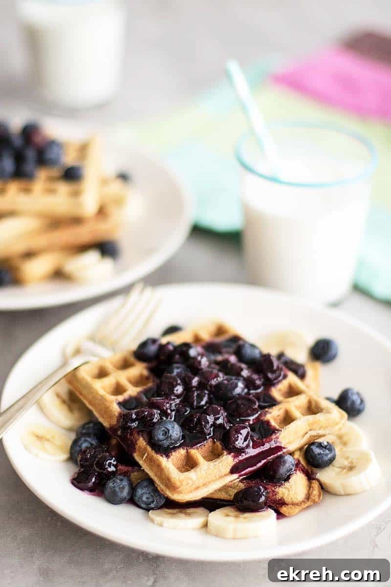 A stack of waffles topped with blueberry syrup.