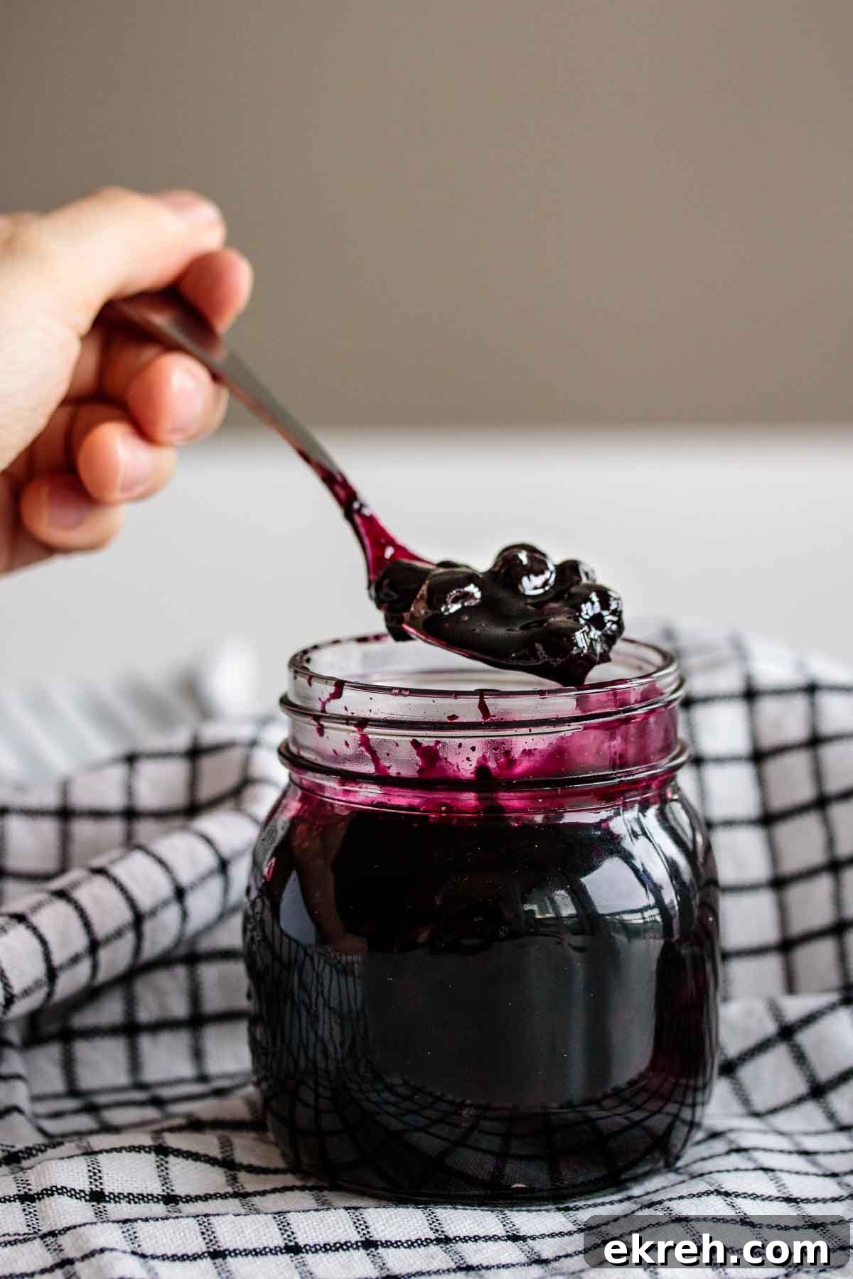 Blueberry Compote for Cheesecake Without Cornstarch 5 A hand holding a spoon full of compote