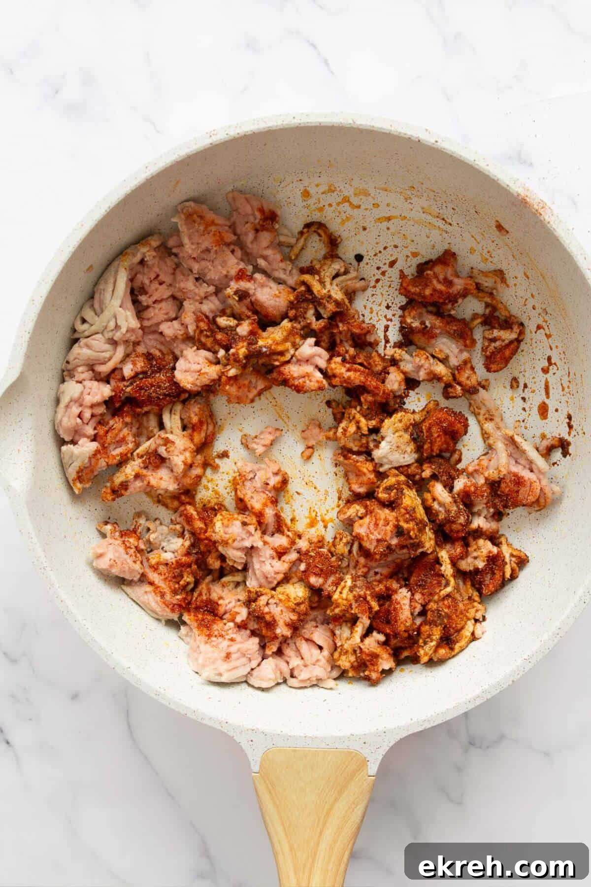 Cooking raw ground turkey with the homemade seasoning in a pan.