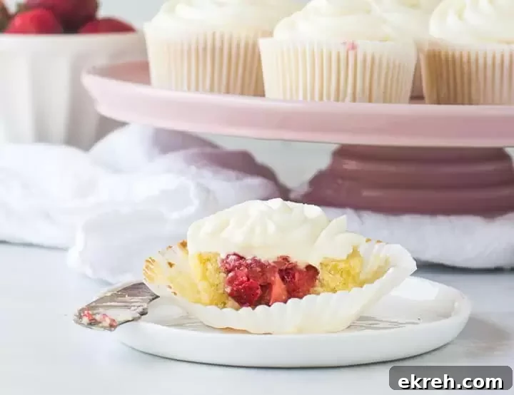 cupcake sliced in half on a plate with more strawberry shortcake cupcakes in the background