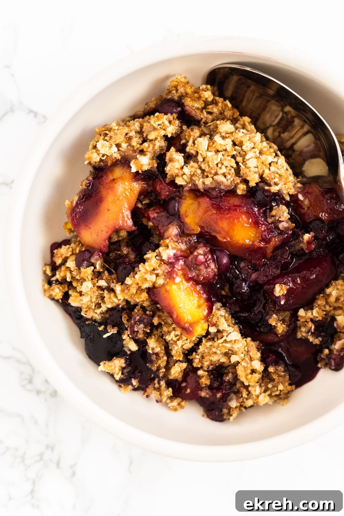 A top down view of a bowl of chai mango blueberry crisp.