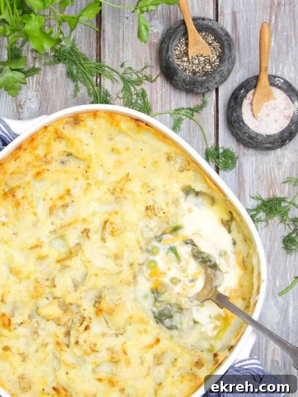Fish pie being served with a spoon on a wooden table.
