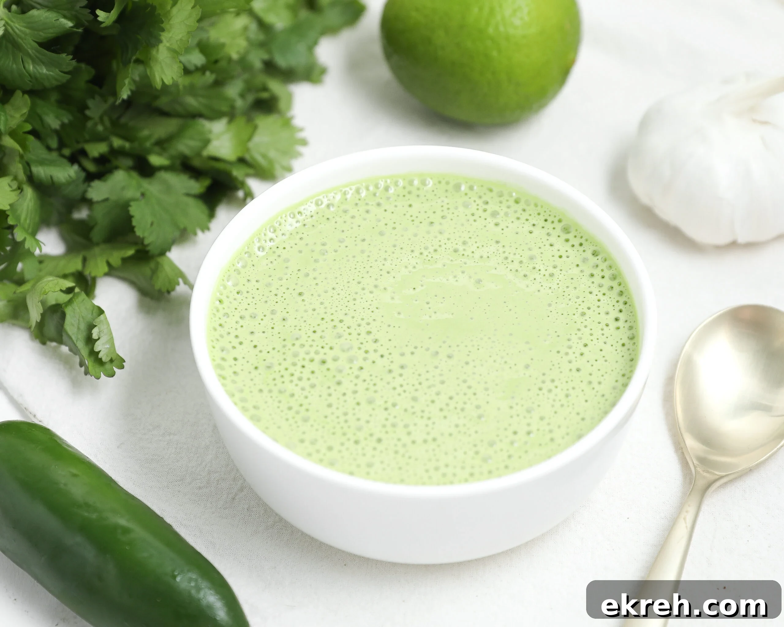 Peruvian Aji Verde: Green Sauce for Any Dish 2 Bowl of creamy Peruvian green sauce with cilantro, lime, garlic, and jalapeño nearby.