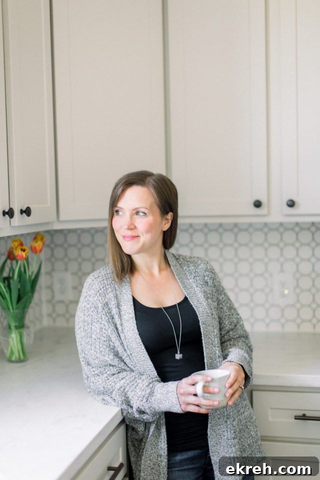 Blog creator, Erin Jensen, holding a white mug and standing in a kitchen.