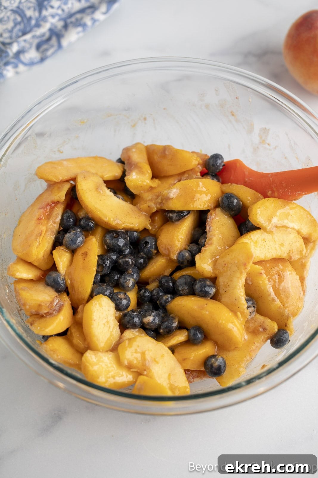 Sliced peaches and blueberries in a glass mixing bowl. 