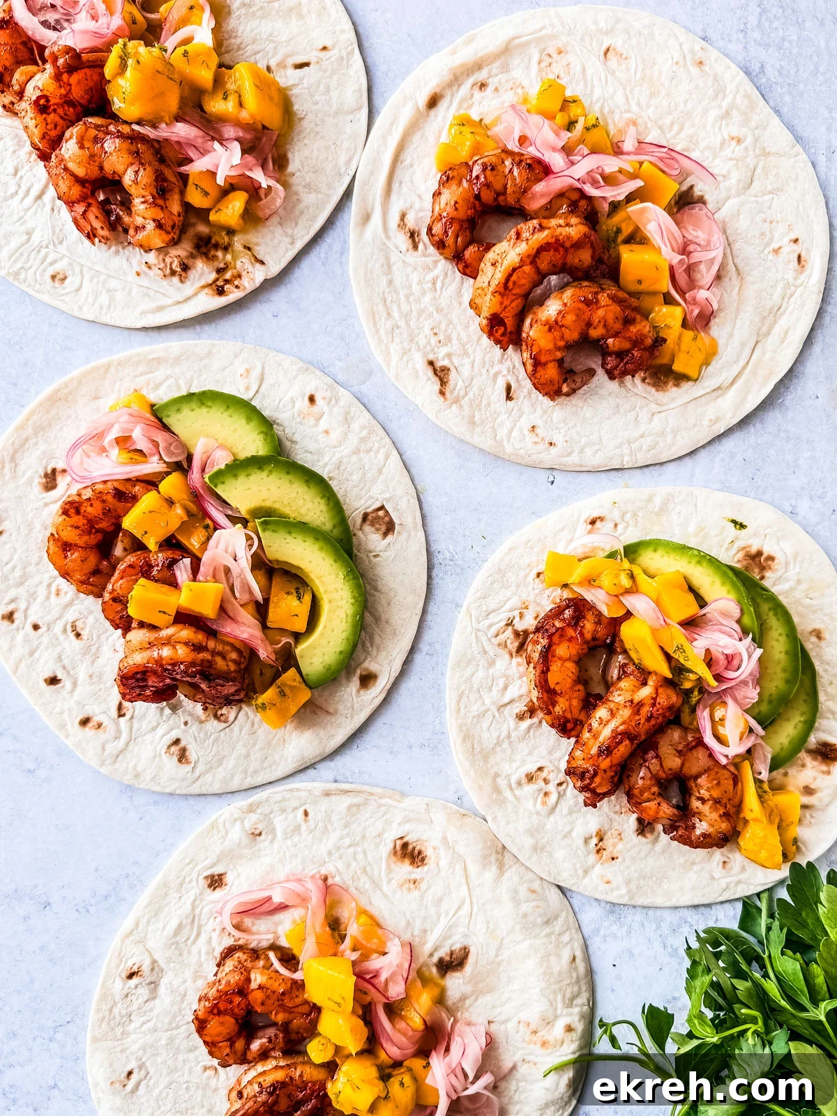 Soft taco shells topped with shrimp, pickled onions, mango salsa, and avocado. 