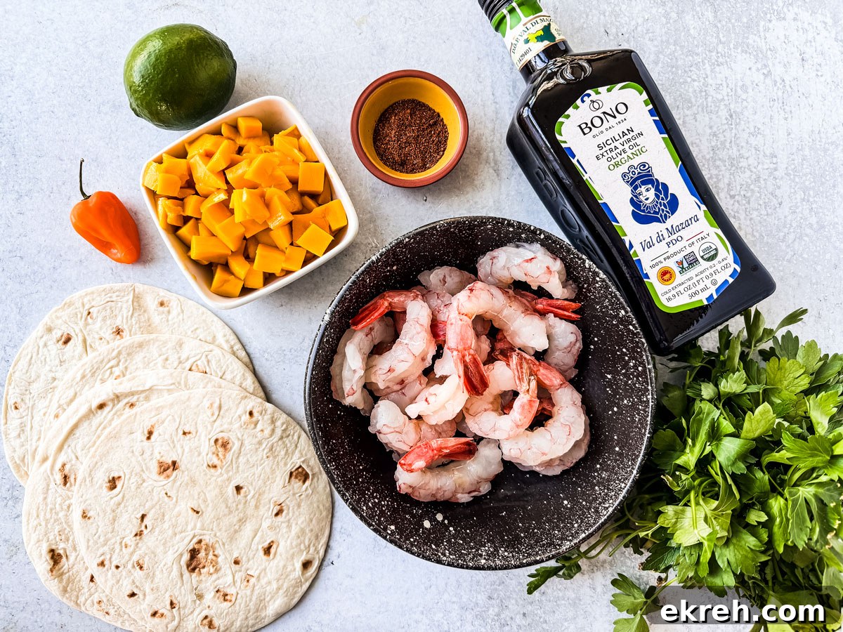 Ingredients for spicy shrimp tacos with mango salsa on a light stone background.