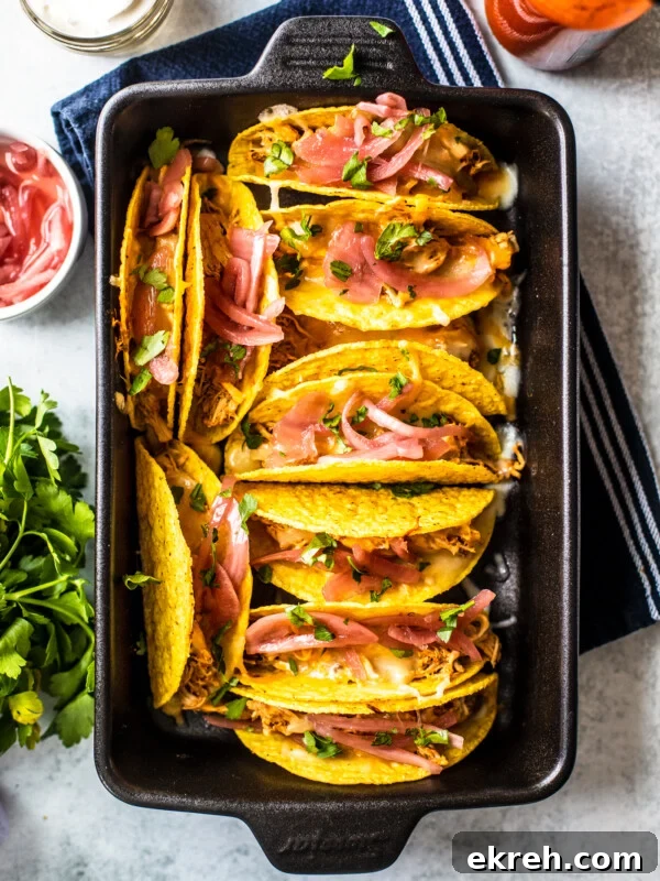 Cast iron baking dish filled with cheesy baked shredded chicken tacos.