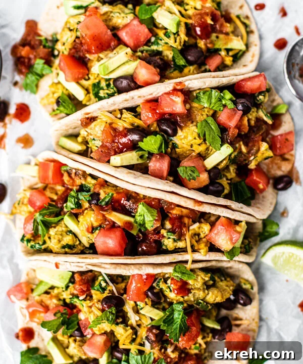 Loaded breakfast tacos full of scrambled eggs and veggies drizzled with hot sauce.
