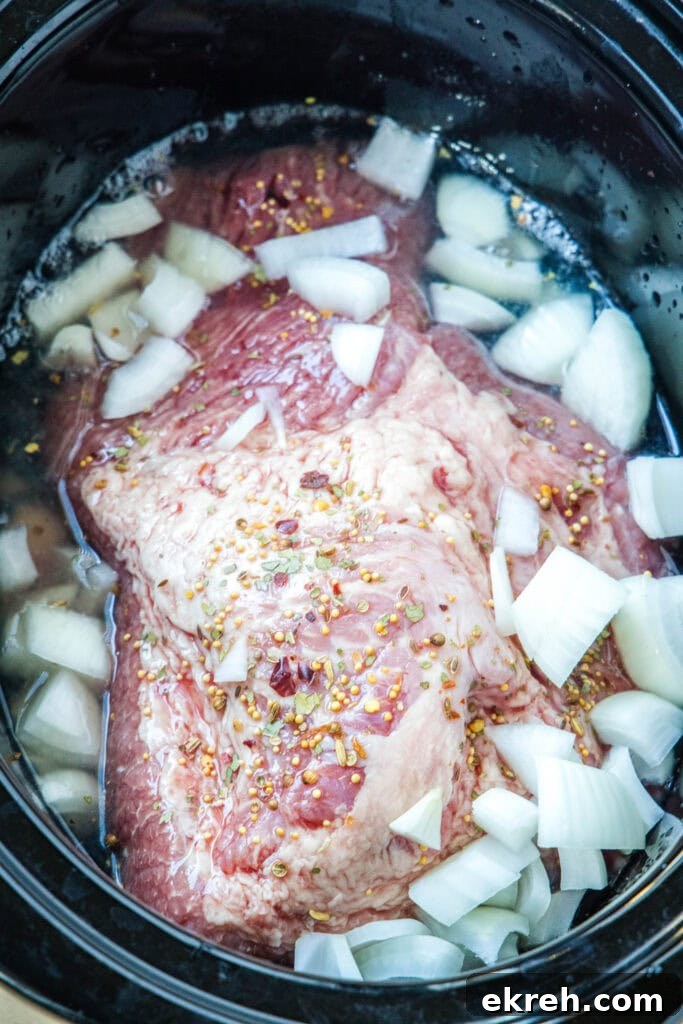 Onions on corned beef Chopped onions added over top of corned beef brisket in the slow cooker.
