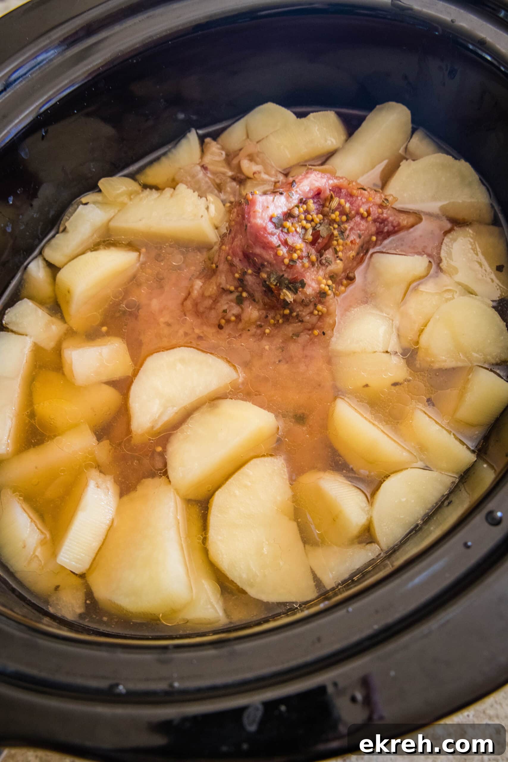 Cooked corned beef and potatoes Cooked corned beef, onions, and potatoes inside the slow cooker.
