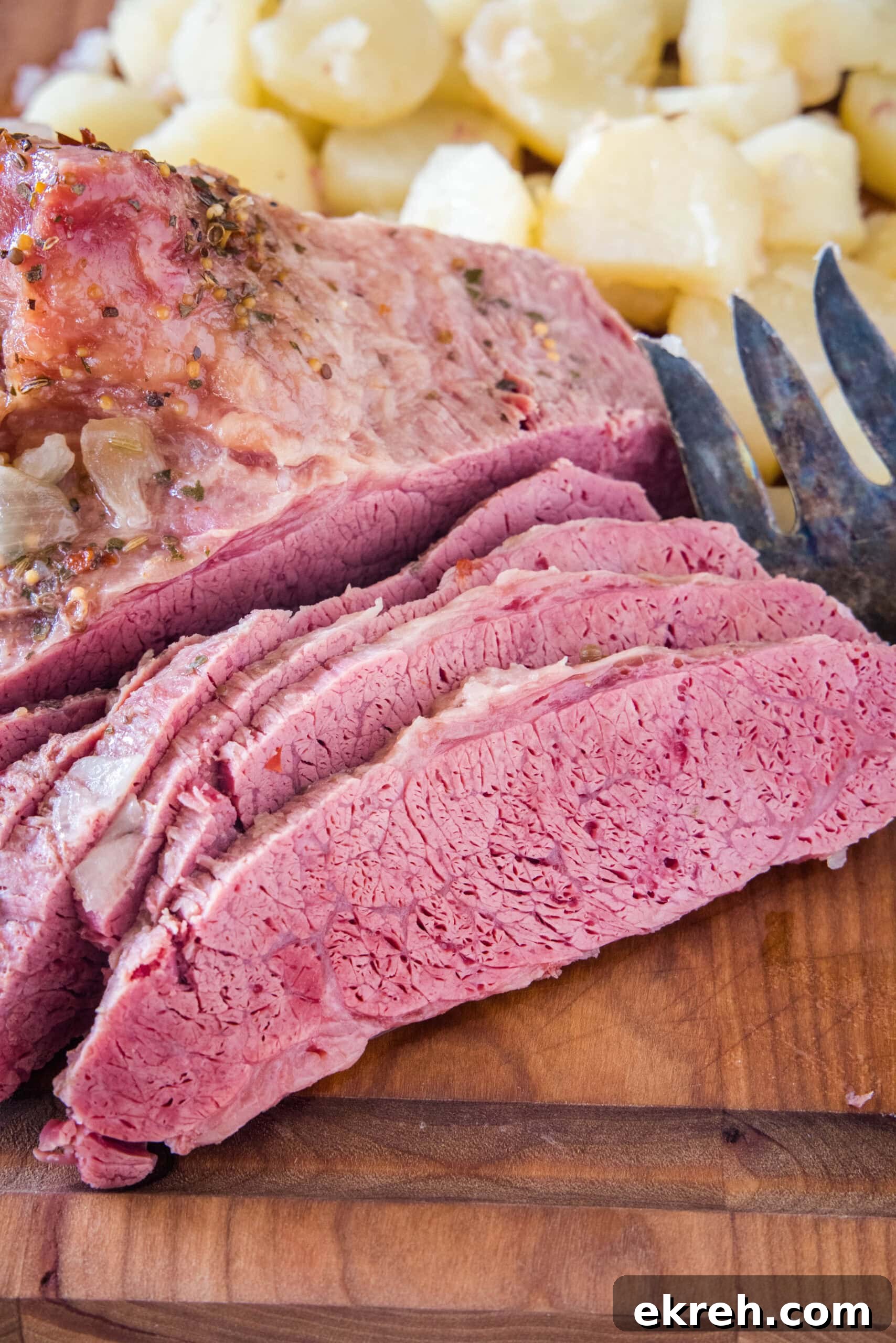 Sliced corned beef Sliced corned beef next to cooked onions on a wooden cutting board.