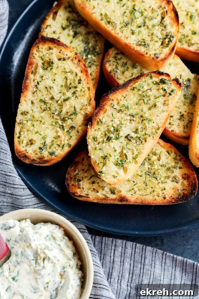 Crispy Sourdough Garlic Toast with Herb Butter 3 slices of sourdough garlic toast on a plate next to a bowl of butter